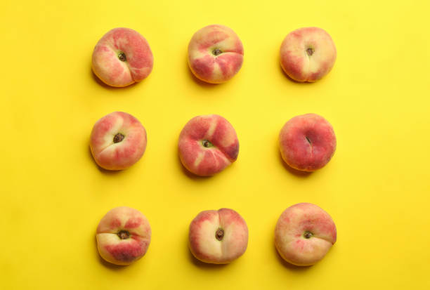 Fresh donut peaches on yellow background, flat lay