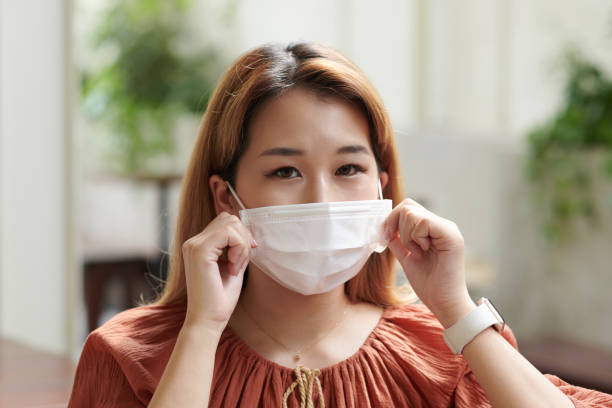istock Woman Putting on Protective Medical Mask 1361283519