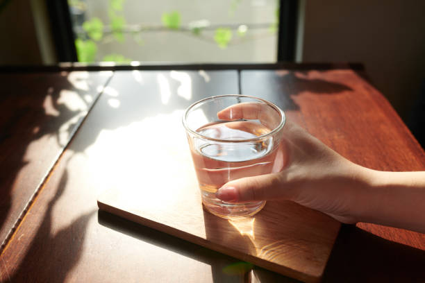 Close-up image of woman drinking glass of fresh water before starting working day