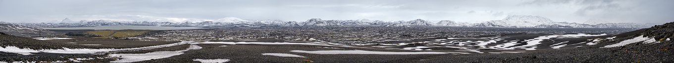 Iceland highlands autumn ultrawide view. Lava fields of volcanic sand in foreground. Hrauneyjalon lake and volkanic snow covered mountains in far.