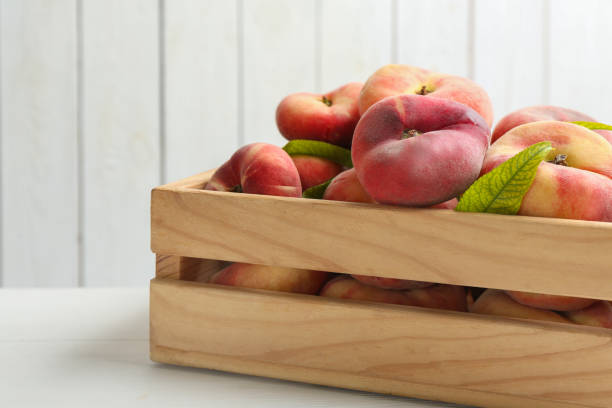 istock Fresh ripe donut peaches in crate on white wooden table 1361285015
