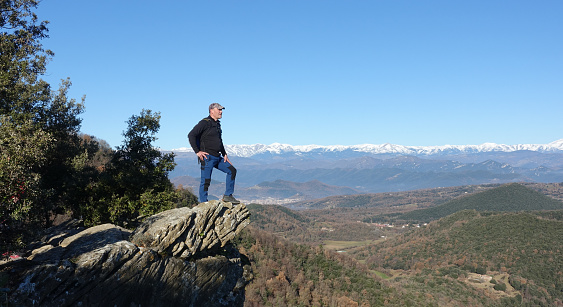 From the top of a hill you can see the volcanic area of ​​La Garrotxa, with its villages and its capital, Olot. In the background, the Pyrenees mountains are covered with snow.