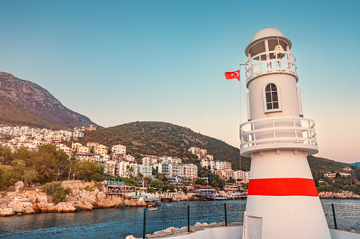 Romantic lighthouse at the entrance to the bay and port of Kas fishing and resort town on the Mediterranean coast of Turkey. Sunset and golden hour time