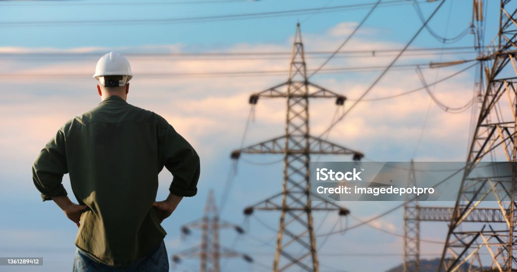 Power line support technology maintenance and development industry concept Power line and worker over sky Electrical Grid Stock Photo
