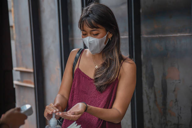istock Indonesian woman using hand sanitizer upon arrival in a restaurant 1361291036