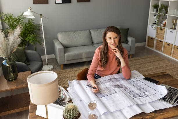 Shot of an attractive young architect working in her office. Shot of an attractive young architect working in her office. Designing a new real estate. Female architect working at home.She looking at blueprint. Female architect. Young woman working on a project architect stock pictures, royalty-free photos & images