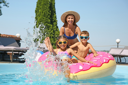 Woman with her children in swimming pool. Family vacation