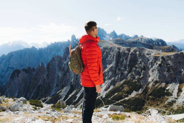 istock Young man backpacker hiking in Dolomites Alps mountains during bright sunny day 1361296053