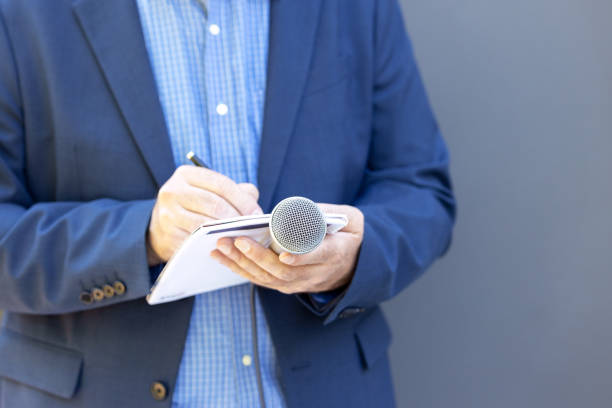 istock Journalist at press or news conference, holding microphone, writing notes. World press freedom day concept. 1361296796