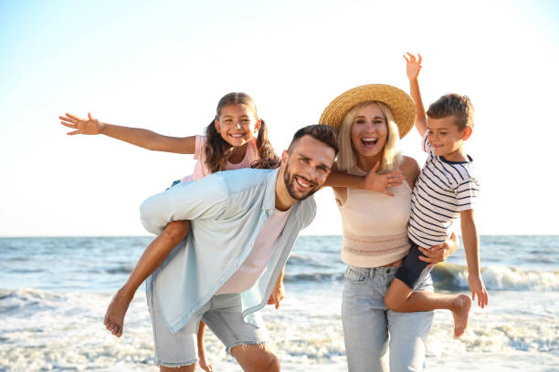 glückliche familie am strand in der nähe des meeres. sommerferien - couple two parent family beach loving stock-fotos und bilder