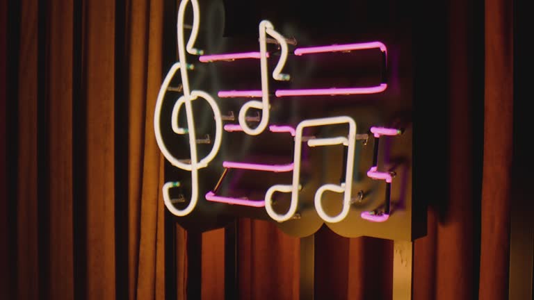 Retro style neon musical note sign hanging on the wall in club or pub . Colorful neon flashing lights on vintage signboard or banner . Slow motion . Close up shot . Camera moving