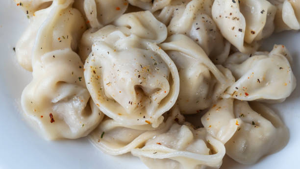 Boiled meat dumplings. Close-up view of russian boiled pelmeni on white plate. Boiled meat dumplings. Close-up view of russian boiled pelmeni on white plate. Boiled prepared homemade russian dumplings or pelmeni with beef meat. russian pelmeni stock pictures, royalty-free photos & images