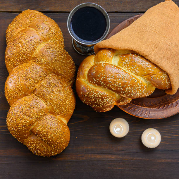 Shabbat Shalom challah bread, shabbat wine and candles on wooden table stock photo