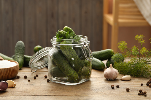 Pickling jar with fresh cucumbers on wooden kitchen table
