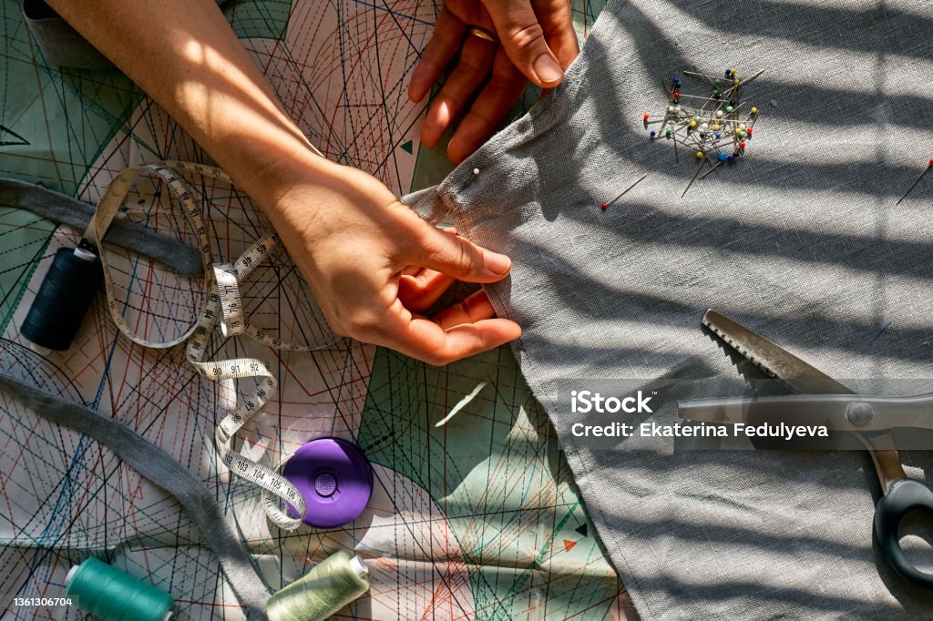 Woman is sketching pattern on a linen fabric Seamstress basting and sewing in a small studio Sartorial clothes Fashion studio, tailoring, handmade clothing concept Slow fashion Conscious consumption Fashion Stock Photo