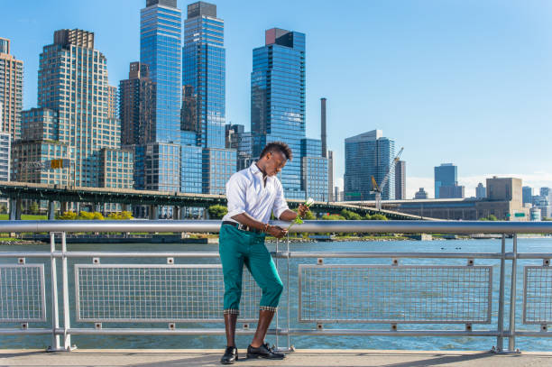 joven negro con cabello mohawk de pie al aire libre en la ciudad de nueva york, sosteniendo rosa blanca, pensando. - mohawk river fotografías e imágenes de stock