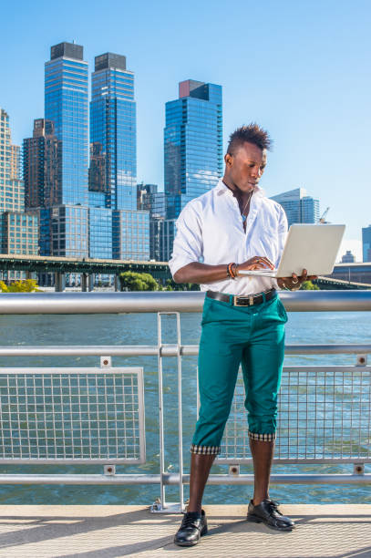 young black man with mohawk hair traveling in new york city, working on laptop computer - mohawk river imagens e fotografias de stock