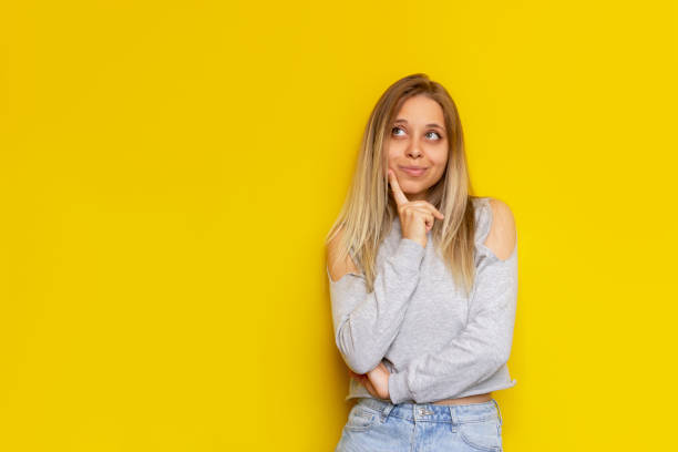 istock A young thoughtful blonde woman thinks about something looking away at empty copy space on a color yellow background 1361307939