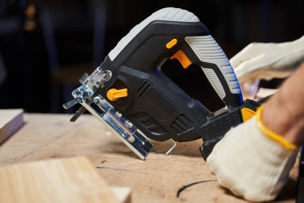 istock jigsaw with a battery on a workbench and nearby male hands in work gloves 1361308017