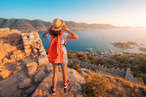 Woman traveler explores the ruins of the castle of Simena with a view of the sea bay and Kekova Island with the famous flooded city. Tourist attractions in Turkey