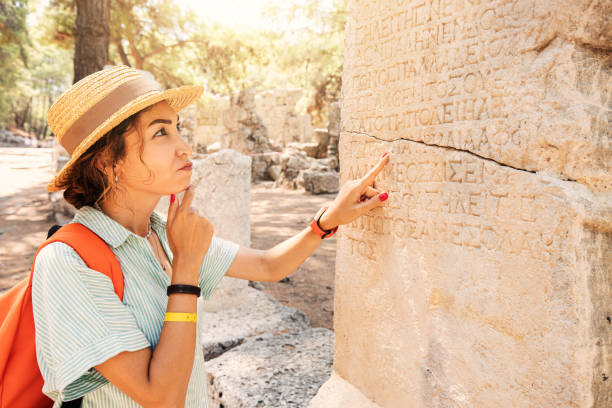 une femme philologue et touriste lit et essaie de traduire le grec ancien à partir de colonnes dans les ruines d’une ville antique. linguistique et archéologie - column greek culture roman architecture photos et images de collection