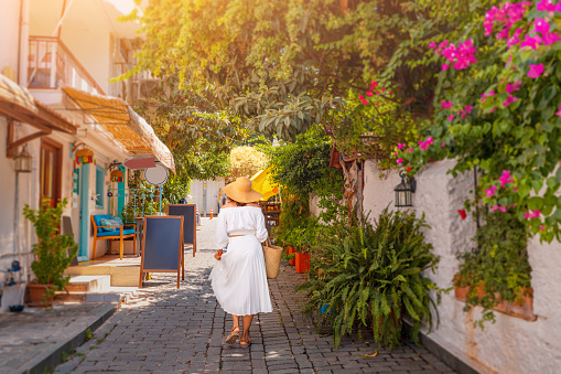 Woman tourist walks through the picturesque streets of the coastal and resort town of Kas with its famous white houses. Travel attractions of Turkey
