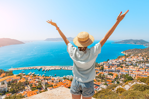 Mujer feliz con los brazos abiertos se para en el mirador y disfruta del panorama de la ciudad turística de Kas del mar Mediterráneo en Turquía photo