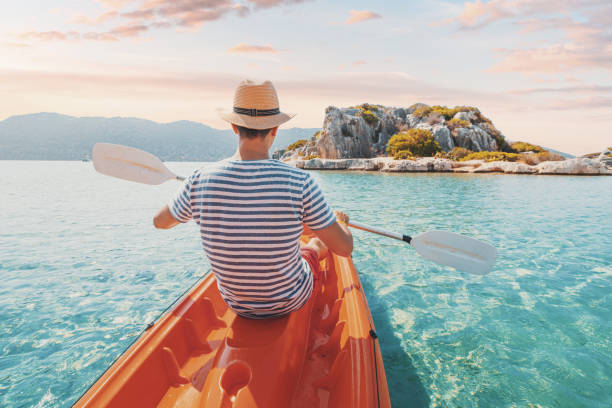 Happy man traveler kayaks near an ancient sarcophagus and a Lycian tomb in the flooded city of Kekova in Turkey. A pleasant and healthy vacation on the coast Happy man traveler kayaks near an ancient sarcophagus and a Lycian tomb in the flooded city of Kekova in Turkey. A pleasant and healthy vacation on the coast kekova stock pictures, royalty-free photos & images