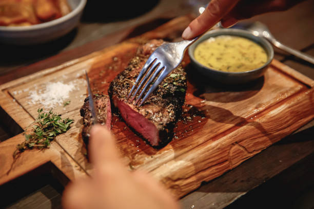mujer irreconocible comiendo bistec en restaurante de alta gama - roast beef fotos fotografías e imágenes de stock