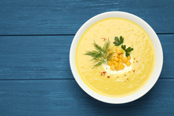 istock Delicious creamy corn soup served on blue wooden table, top view. Space for text 1361312065