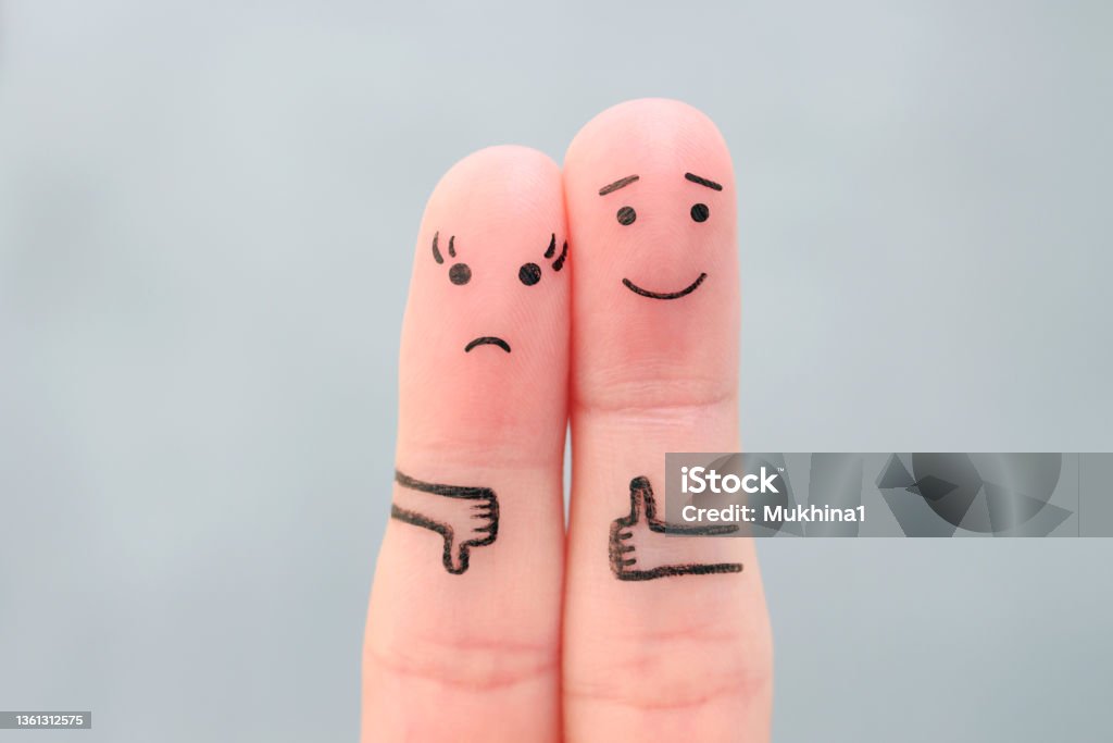 Fingers art of couple. Woman showing thumb down and man showing thumb up. Concept of disagreement in family. Contrasts Stock Photo