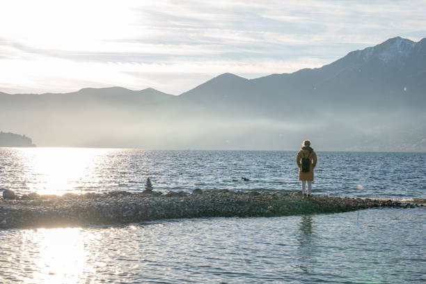 istock Distant woman contemplates magnificent lake scenery 1361316383