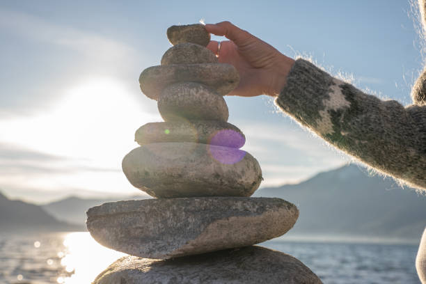 istock Close up on woman's hand stacking rock by the lake 1361317100