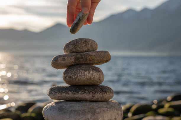 istock Close up on woman's hand stacking rock by the lake 1361317664