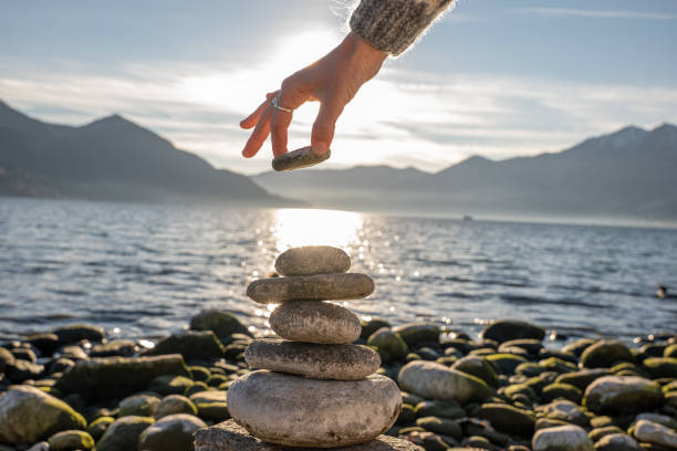 istock Close up on woman's hand stacking rock by the lake 1361317666