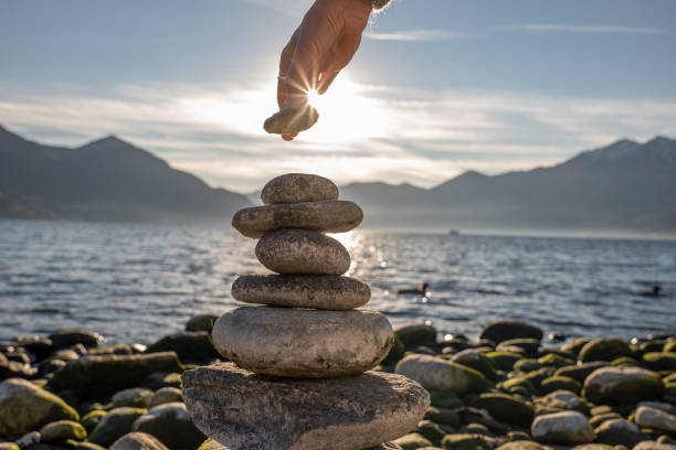 istock Close up on woman's hand stacking rock by the lake 1361320027