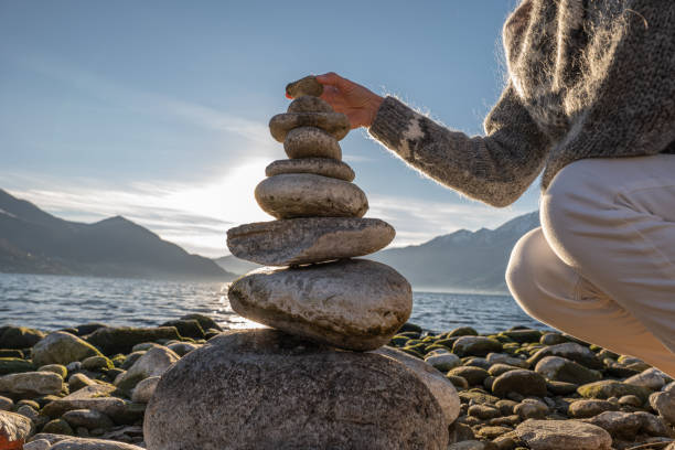 istock Close up on woman's hand stacking rock by the lake 1361320113