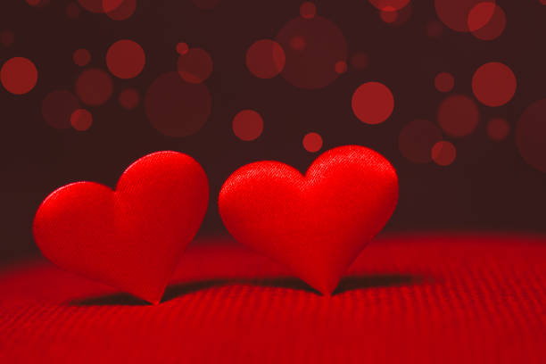 Red decorative hearts on glitter against blurred lights, closeup