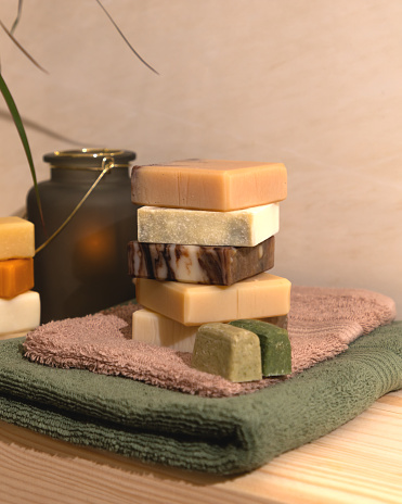 Organic solid hair shampoo and handcrafted soap with all natural plant-based essential oils on a wooden bathroom shelf. A candle in a beautiful candlestick for relaxation. Home spa concept.