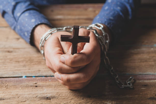 prisoner in chains praying powers cross prisoner in chains praying powers cross clergy stock pictures, royalty-free photos & images