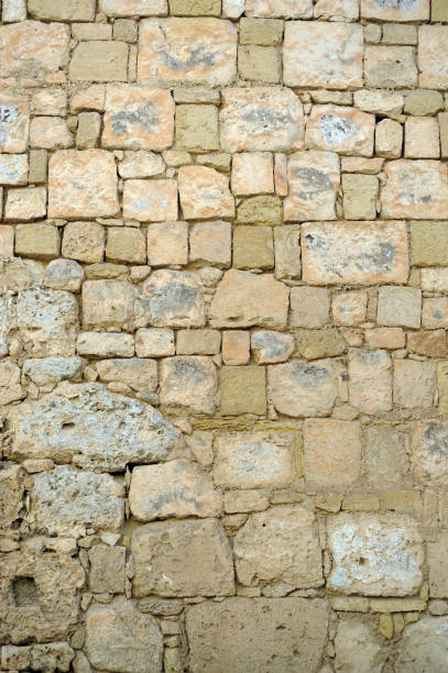 Rough hewn ancient stone wall of Mdina, Island of Malta, Mediterranean Sea. Rough hewn ancient stone wall of Mdina, Island of Malta, Mediterranean Sea. Mdina is the ancient fortified city ii the centre of Malta. Malta is a central Mediterranean archipelago between Sicily and the North African coast, known for its mellow sandstone architecture and historic sites reflecting the styles of rulers that include the Romans, Moors, Knights of Saint John, French and British roughhewn stock pictures, royalty-free photos & images