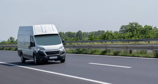 biała nowoczesna dostawa małych przesyłek kurierskich poruszających się szybko po autostradzie do miejskiego przedmieścia miasta. - delivery van truck delivering moving van zdjęcia i obrazy z banku zdjęć