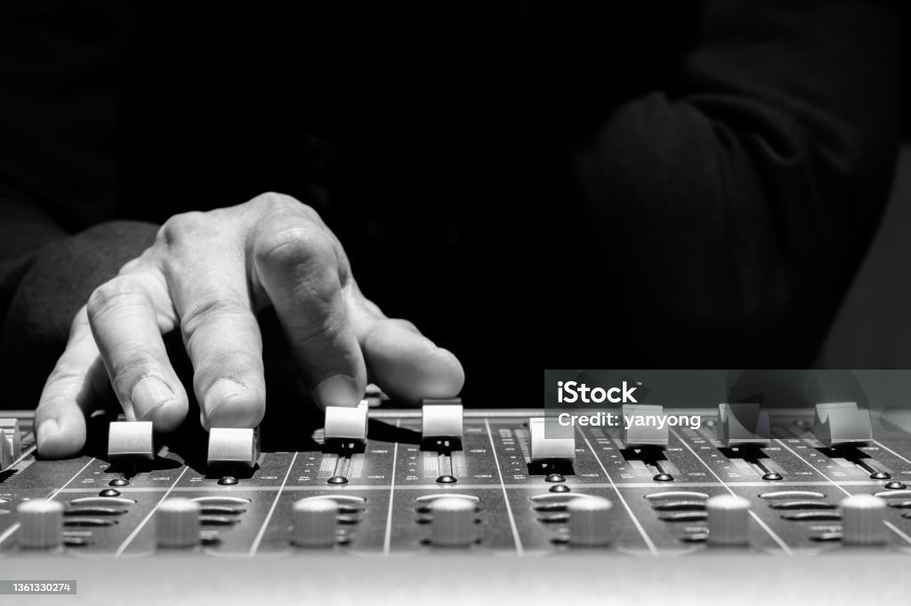 close up sound engineer hands adjusting control surface mixer in recording, broadcasting studio Noise Stock Photo
