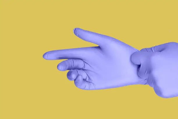 Purple gloves on a hand on a yellow background