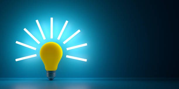 istock Yellow bulb with light beams on dark surface with copy space 1361339584