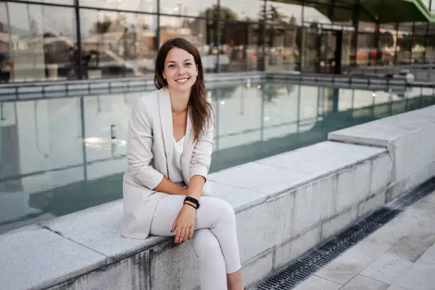 Portrait of a beautiful white business woman sitting near the fountain