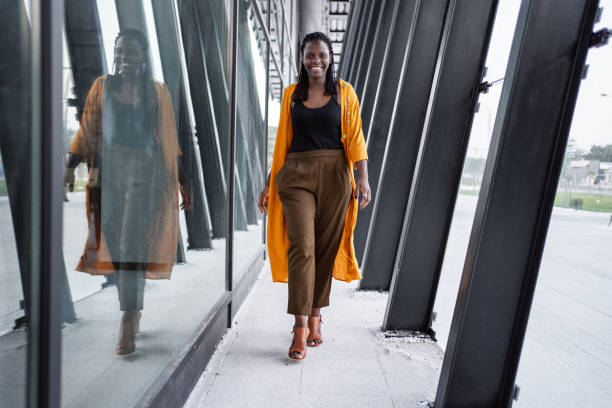 retrato de una mujer de negocios negra caminando cerca del edificio de oficinas - acercarse fotografías e imágenes de stock