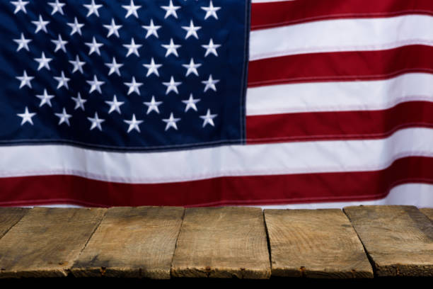 istock Empty wooden table top with USA flag on background. 1361351584