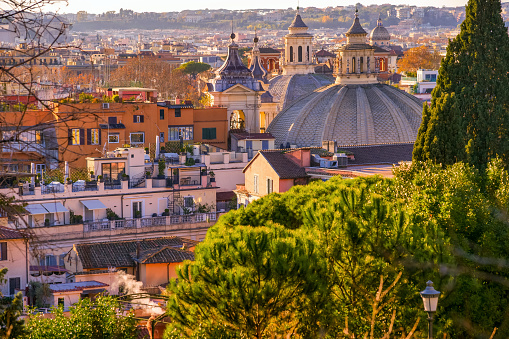 A beautiful view over the roofs and domes of Rome seen from the Pincio Gardens viewpoint, in the historic center of the Eternal City. On the right, the baroque-style domes of the two twin churches of Piazza del Popolo, namely the Basilica of Santa Maria in Montesanto (in the foreground) and the church of Santa Maria dei Miracoli. The terrace viewpoint of the Pincio Gardens, one of the most visited and loved places in Rome, is the culmination of the west side of Villa Borghese, the largest public park of the Italian capital. From this belvedere you can enjoy a breathtaking 180 degree view of the historic center of Rome, in the setting of some of the most beautiful gardens in the city. In 1980 the historic center of Rome was declared a World Heritage Site by Unesco. Image in high definition format.