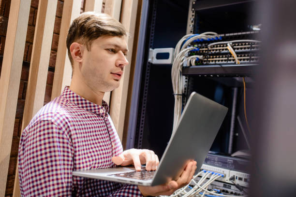 in the server room a technician/ it engineer/ hold the notebook - computer plan fiber optic engineer imagens e fotografias de stock